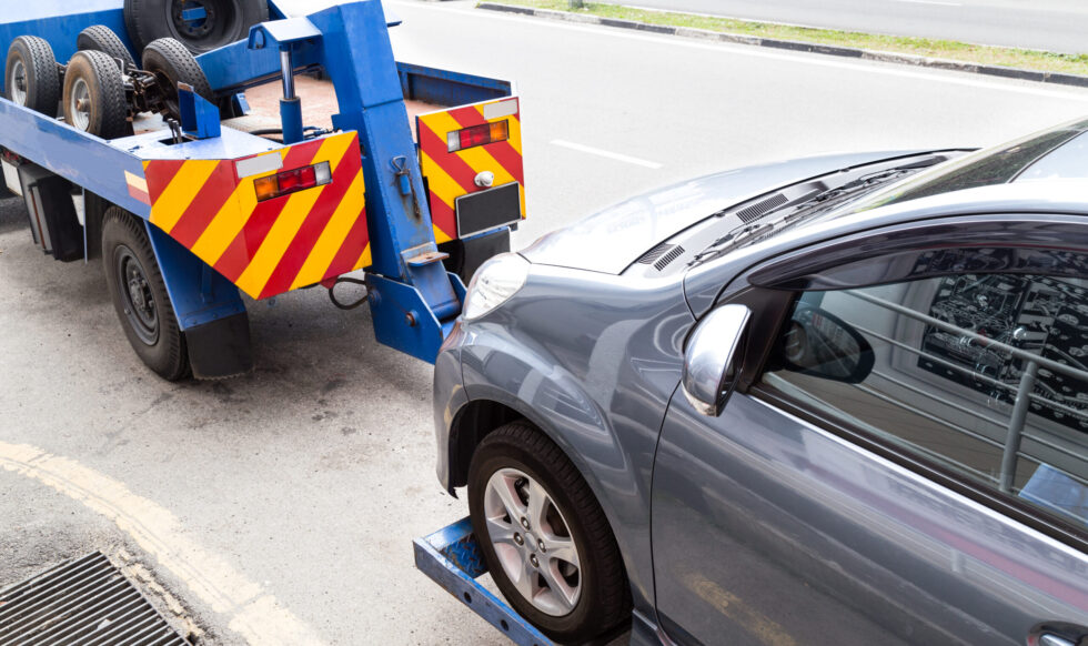 Tow truck towing a broken down car on the street Tow truck towing a broken down car on the street.